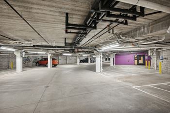 a large parking garage with a purple door and pipes hanging from the ceiling